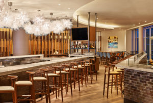Bar with stools, intricate light fixtures, and flat screen tv